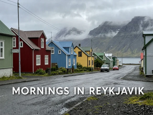 A quiet street in a small Icelandic coastal town with the caption MORNINGS IN REYKJAVIK added in bold white text along the lower third of the photo