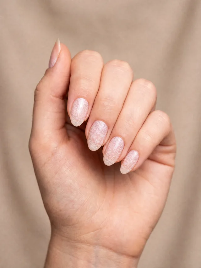 Ongles rose laiteux translucide ornés d'un fin filigrane de dentelle blanche peint sur chaque ongle